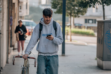 student with mobile phone on the street walking with the vintage bicycle