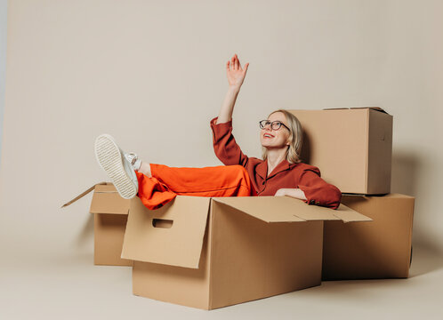 Smiling businesswoman sitting in carton box and day dreaming against white background