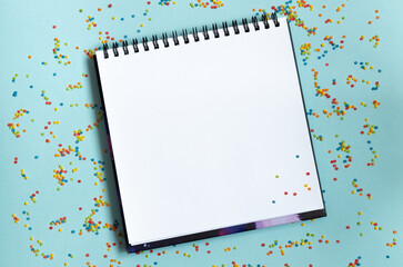 White open notebook on colorful background, festive, multicolored paper confetti. - obrazy, fototapety, plakaty