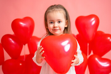 Happy Valentine's Day heart. The baby is holding a red balloon in the shape of a heart. Pink background