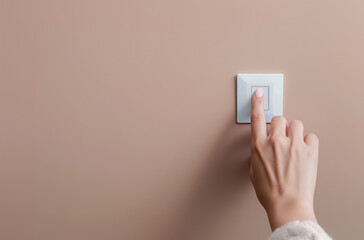 Female hand turning on a light switch. A close-up view of a female hand pressing a white light switch on a beige wall