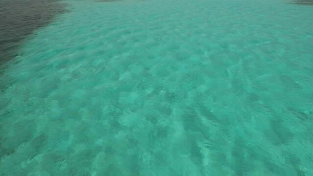 Flying shot over steady, clear ocean water of Belize
