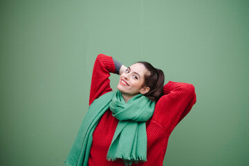 Smiling woman with hands behind head against green background