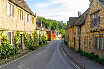 Scenic view of traditional old cottage houses and a street by a river in a beautiful English village, Castle Combe village in the Cotswolds Area of Outstanding Natural Beauty in Wiltshire, England. - obrazy, fototapety, plakaty
