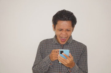 Young Asian man wearing a black shirt angry and pointing at smartphone isolated on white background.