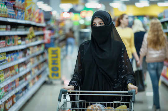 Portrait d'une jeune femme d'origine arabe islam portant la bourka faisant ses coursesq dans un supermarch&eacute; avec un caddie