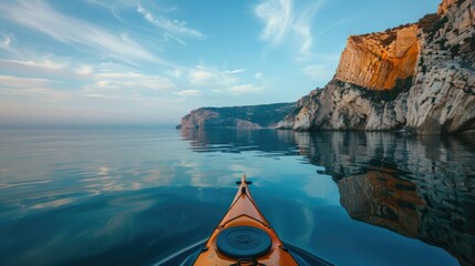 Beauty of a peaceful ocean kayaking adventure The kayak glides silently across the calm,glassy waters near the shore,reflecting the rugged cliffs and cloudy - obrazy, fototapety, plakaty