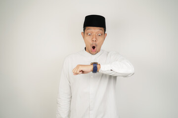 Asian Muslim man Wow face shocked expression looking at watch in copy space on isolated background - obrazy, fototapety, plakaty