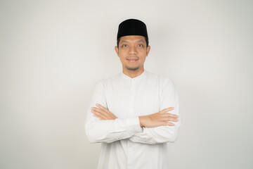 Happy and confident asian muslim man standing with crossed arms on white background - obrazy, fototapety, plakaty