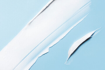 The texture of the skin or hair care product. White smear of cream, mask or balm on a blue...