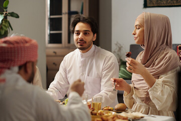 Young Middle Eastern Man Talking To Relatives During Dinner