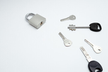 One padlock with many another keys. Many keys and one lock as concept. Different metal keys and one hinged steel padlock on a white background.