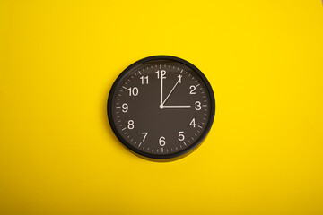 black wall clock on yellow background