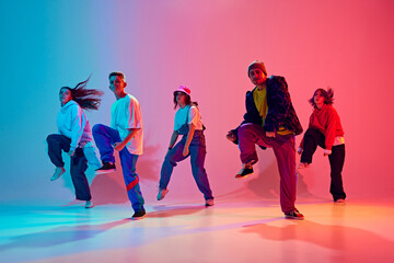 Group of talented dancers practices choreographed number in neon light against gradient colorful...