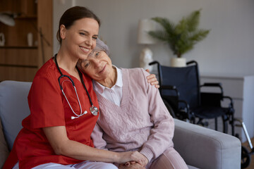 Smiling happily caregiver hugging her old lady patient portrait