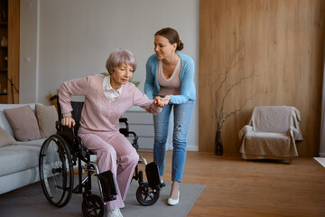 Young daughter helping old mother to move from wheelchair