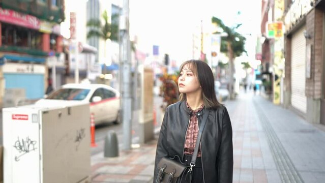 A young Japanese woman from Okinawa Prefecture in her 20s walking alone on Kokusai Street in Naha City, Okinawa Prefecture 沖縄県那覇市の国際通りを一人で歩く20代の沖縄県出身の若い日本人女性