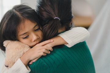 A woman is hugging a child and holding a stuffed animal