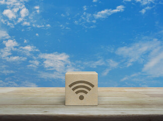 Wi-fi icon on wood block cube on wooden table over blue sky with white clouds, Technology internet communication concept - obrazy, fototapety, plakaty