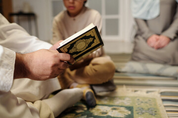 Unrecognizable Man Reading Quran At Family Gathering