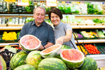 Mature woman and man selecting watermelon in greengrocer