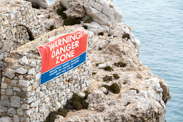 Large banner on the side of an old building along the Gibraltar coastline, waring the public to stay away due to ongoing demolition.