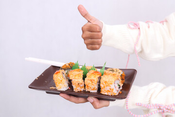 a plate (closeup and front angle) containing a sushi dish (Japanese food) a thumbs up gesture okay held by a woman's hand for culinary, food and lifestyle content