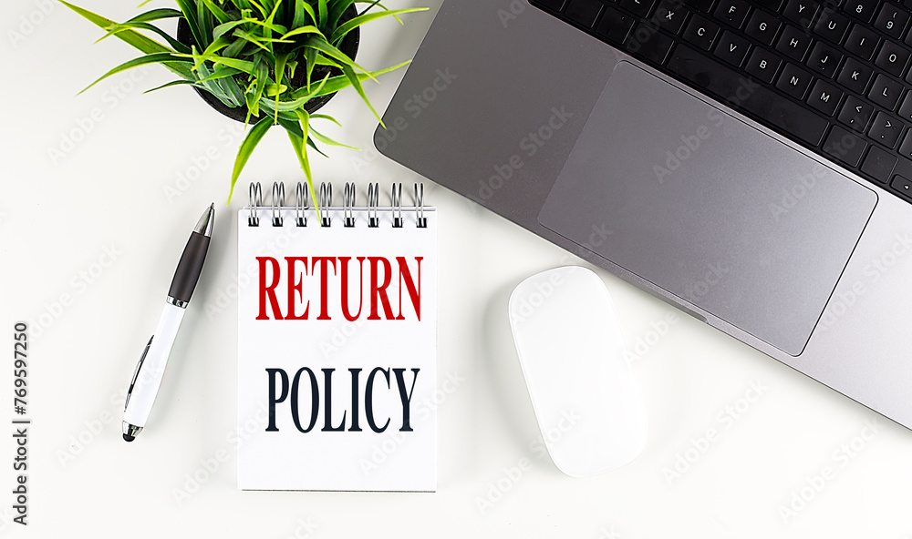 Poster return policy text on notebook with laptop, mouse and pen