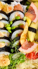 A set of sushi is close. rolls decorated with green beans, a slice of grapefruit, corn chips, micro-greens next to ginger