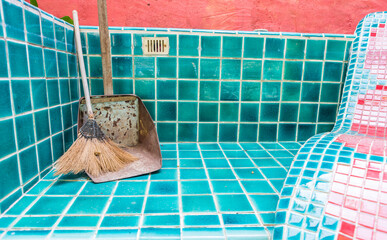 Old broom and rusty old dust pan on swimming pool floor, pool service and maintenance