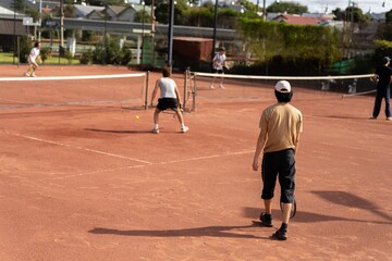 friends playing tennis on a clay court, watering and bagging a clay court. doing tennis court maintence