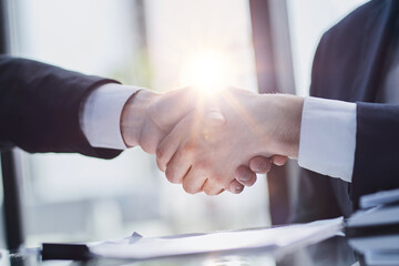 Close up of greeting handshake, young businessman hands shaking over conference table - obrazy, fototapety, plakaty