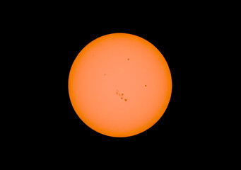 The orange coloured afternoon sun glowing with many sunspots using a homemade solar filter against a black background. March 24, 2014 - 769609639