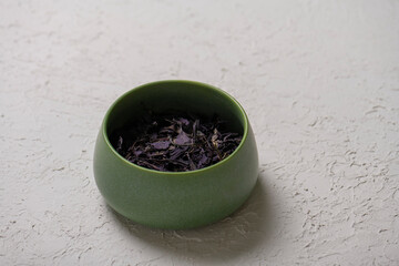 Dry lavender tea in a green bowl on a white background