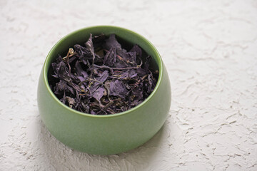 Dry lavender tea in a green bowl on a white background
