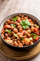 Food dish made of beans, tomatoes, and cilantro on a wooden table