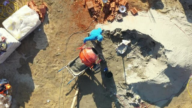 Above top view on building site area, construction worker is using shovel to fill up mixer as making concrete, mortar
