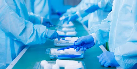 Foto op Plexiglas Closeup of medical staff gloved hands sorting blue med instrument scissors, tool of doctor pharmacy, clear light toning. Banner factory of equipment of surgery © Parilov