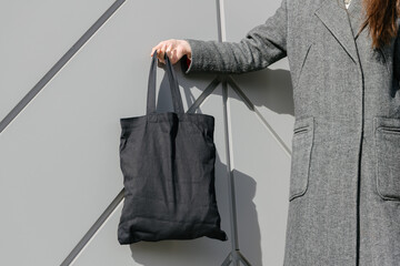 Black tote bag or eco cotton bag in woman's hand