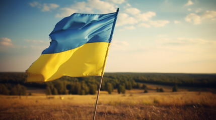 tattered Ukrainian flag flatters in the wind in the field representing Ukraine's resilience  - obrazy, fototapety, plakaty