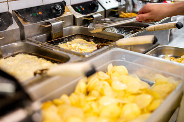 Freshly fried potato chips sizzle in a commercial kitchen, capturing the enticing moment of snack preparation