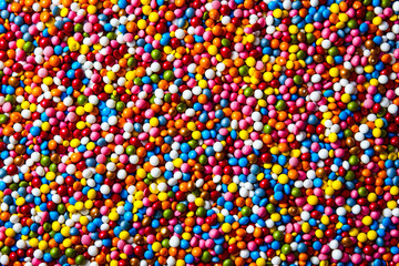 A vibrant, full-frame image of multi-colored candy, depicting a variety of sugar-coated sweets
