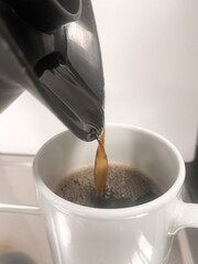 Pouring filter coffee from a jug into a mug