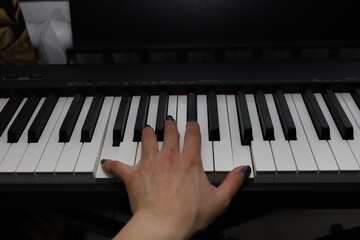 The musician's hand plays a chord on a digital piano. A musician plays a keyboard instrument.
