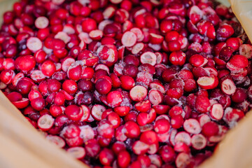 Close-up of a bag full of crimson freeze-dried cranberries, some sliced, with visible frost particles.