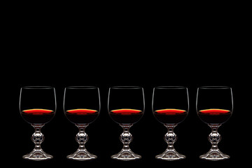 Red grape wine in a glass. On a black background. Glass crystal goblets. Pouring from a bottle. Place for text.