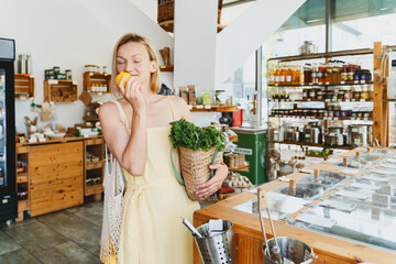 Smiling woman buying organic food and eco products in sustainable plastic free store. Happy female...