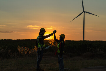 Engineer and energy farming. Wind turbine with the silhouette of sunset background.