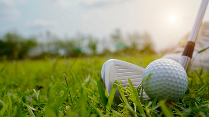 Golf ball and golf club in a beautiful golf course in Thailand. Collection of golf equipment resting on green grass with green background