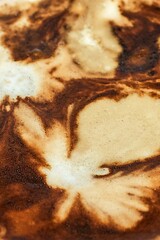 A close-up of a cup of coffee, where the foam creates an abstract and artistic pattern, evoking a feeling of warmth and comfort.